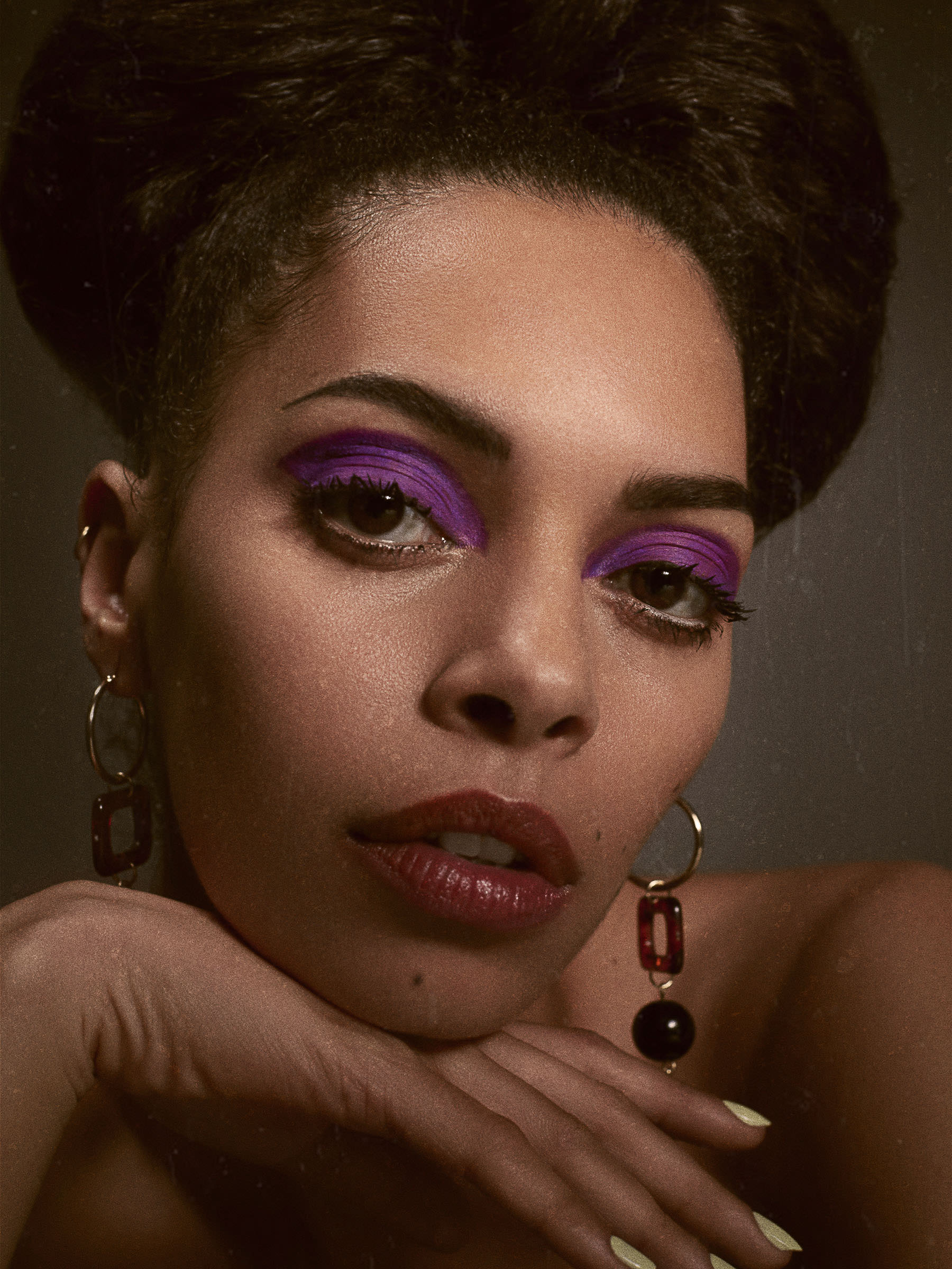 fashion shoot of a woman with purple eyeshadow and curly hair 