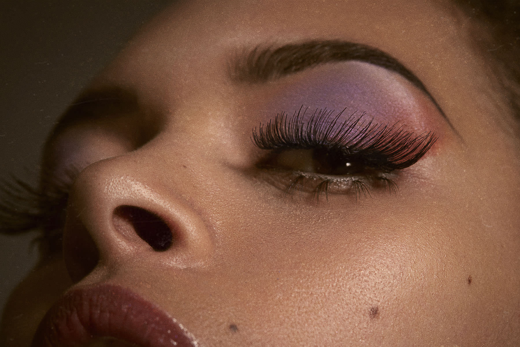 Close-up of a woman with purple eyeshadow and long lashes